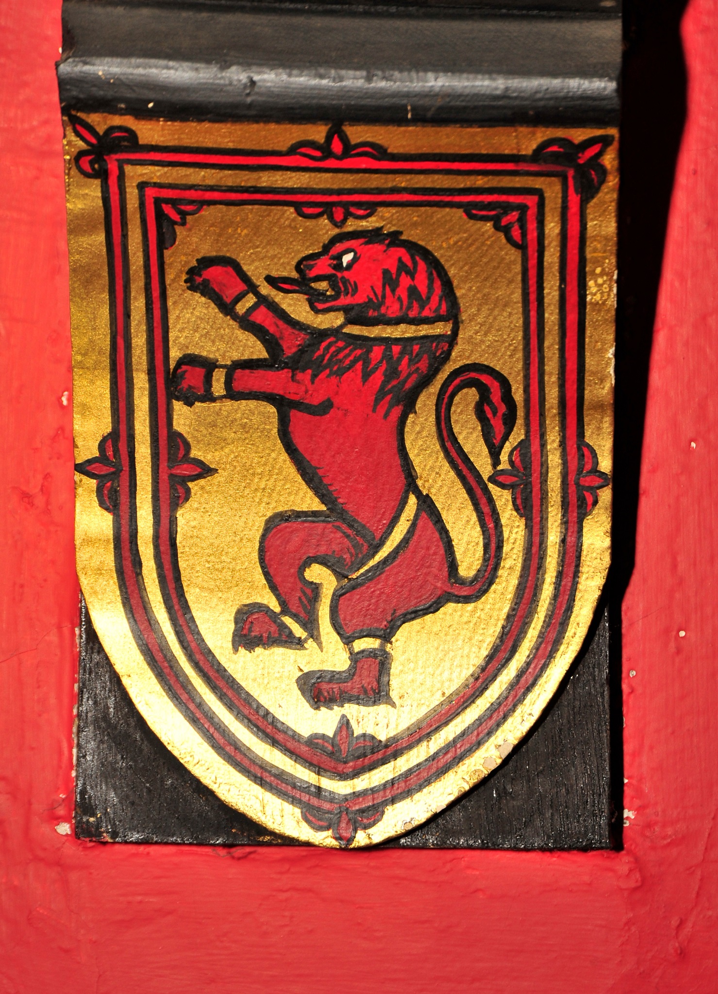 A red lion standing rampant on his hind legs with paws in a stance of attack, across a backdrop of gold. It's the Stuart crest.