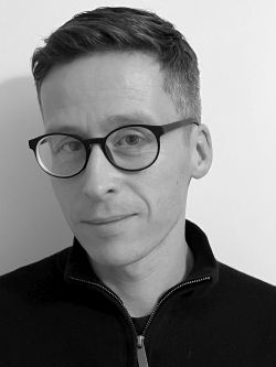 Black and white photo of a man wearing glasses looking at the camera