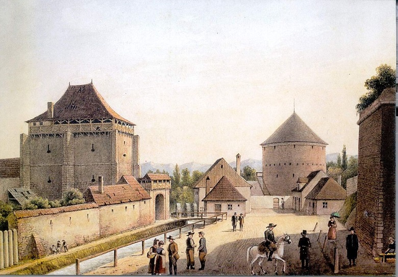 A painting of a part historic European town with medieval houses and a stone gate giving access to a fortress or castle. Various pedestrians and horse riders mill about the streets. 