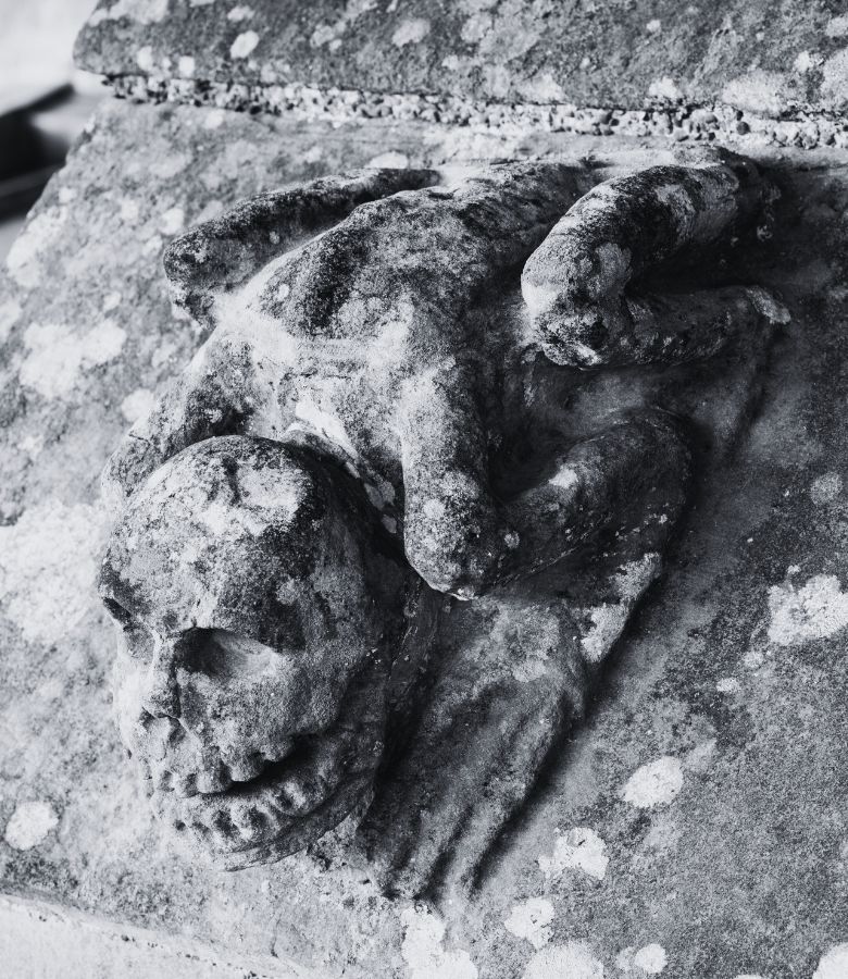 A carved stone greature. It has the body of a frog and the head of grimacing skull.