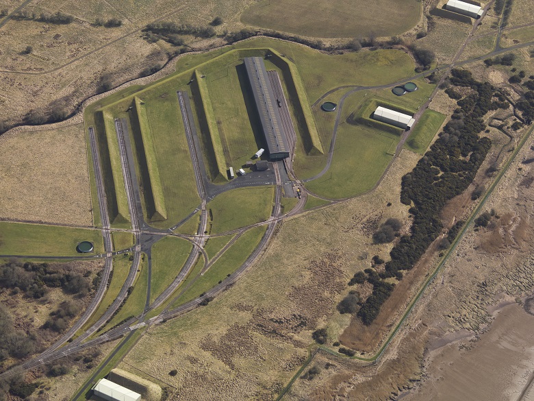 An aerial photo of a railway terminal at a former factory sites. Four sets of tracks curve as they enter long engine sheds. 