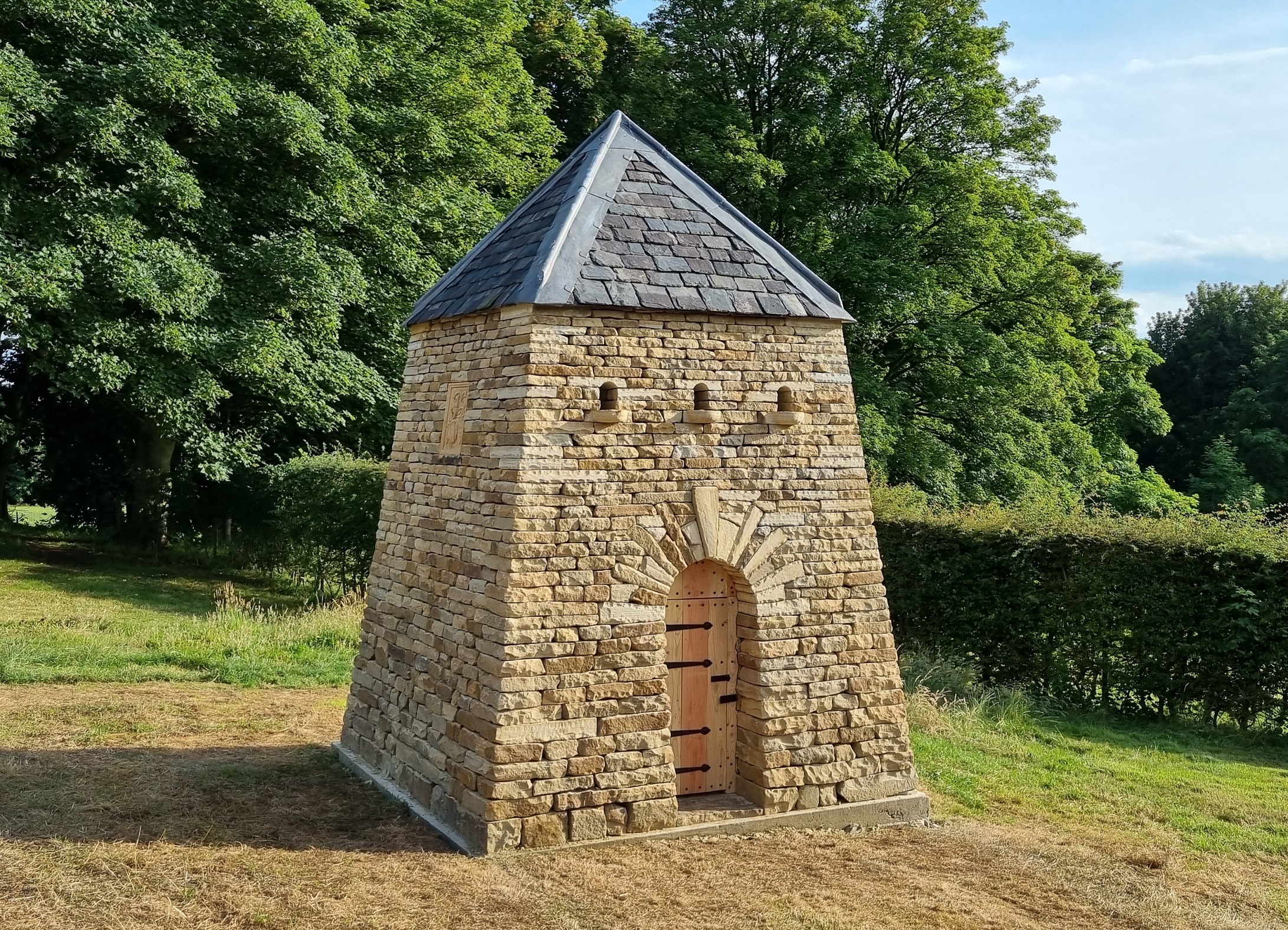 A triangular shaped doocot with a door