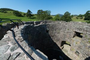 A photograph of the top of Orchardton Tower, at an angle. You can see a grass landscape in the background.