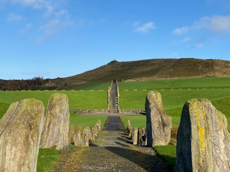 An avenue of standing stones leading to a hill.