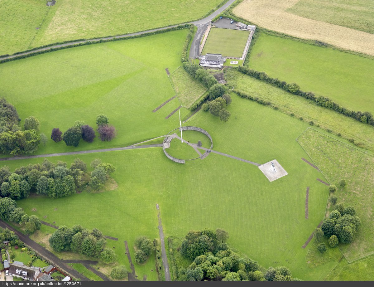 green field from above with circular wall in the middle with a flagpole at the centre and a statue of a man on horseback to the right of this