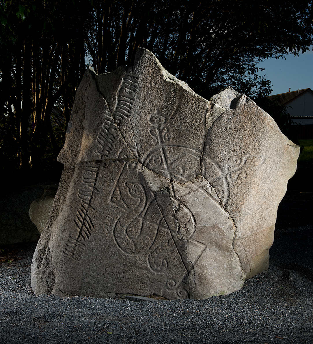 broken stone with a serpent and other shapes carved onto it