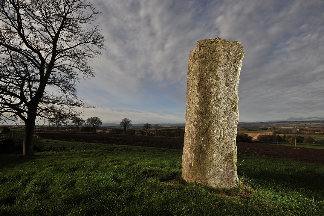 tall grey stone with several carvings on it - double-disc and z-rod, a mirror and comb, and what is thought to be either a wolf or a bear.