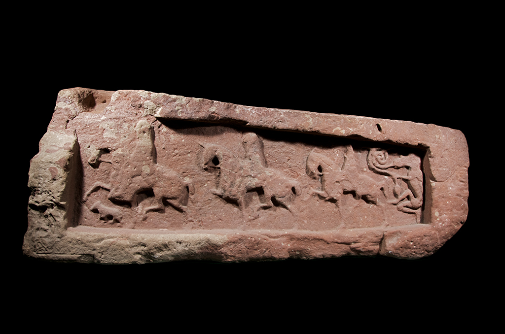 stone with three people on horseback carved on it