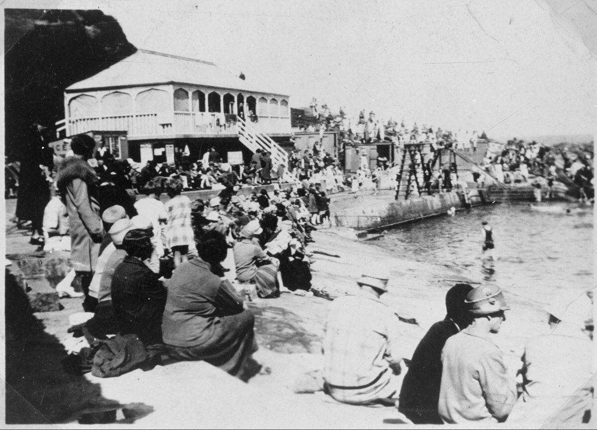 A black and white archive photo of people sitting by the seaside