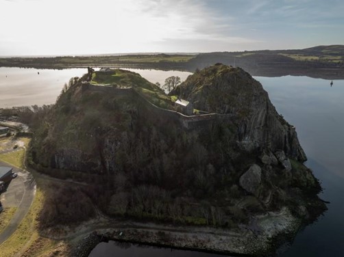 Aerial view of Dumbarton Rock and Castle. It is a sunny day and you can see the water in the background.
