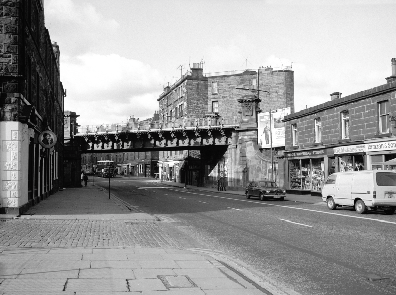 A viaduct above a wide road, in black and white.
