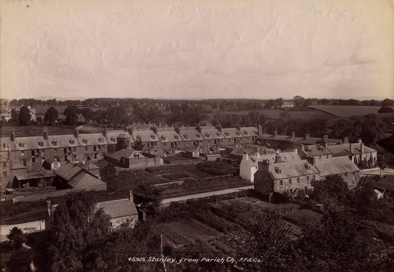 A sepia-toned photograph showing a village scene with rows of houses and gardens. The image is titled "45285 Stanley from Parish Ch. F&Co." The houses are arranged in neat rows with visible chimneys, and there are garden plots in the foreground. Trees and open fields can be seen in the background under a partly cloudy sky.