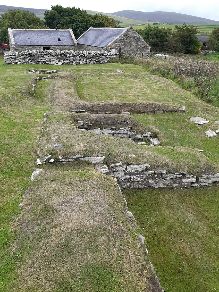 grassy area with series of small walls, the site of the Earl's Bu (another word for farm) at Orphir