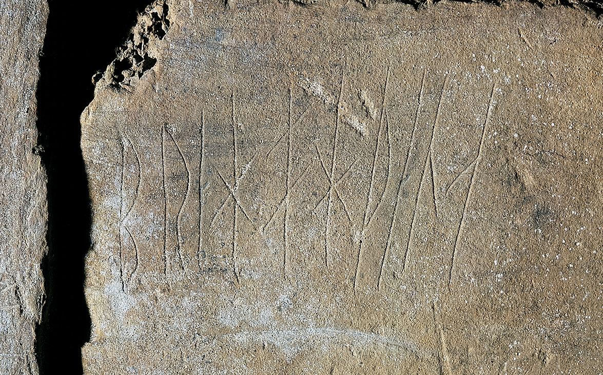 viking rune symbols carved into a grey rock