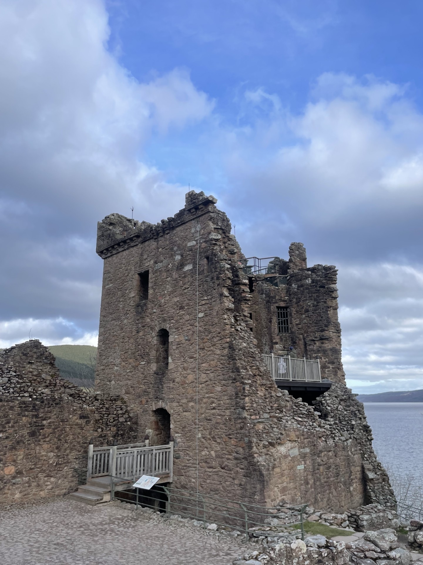 A tall stone tower from Urquhart Castle shown in detail, with weathered stone walls and platforms overlooking Loch Ness.
