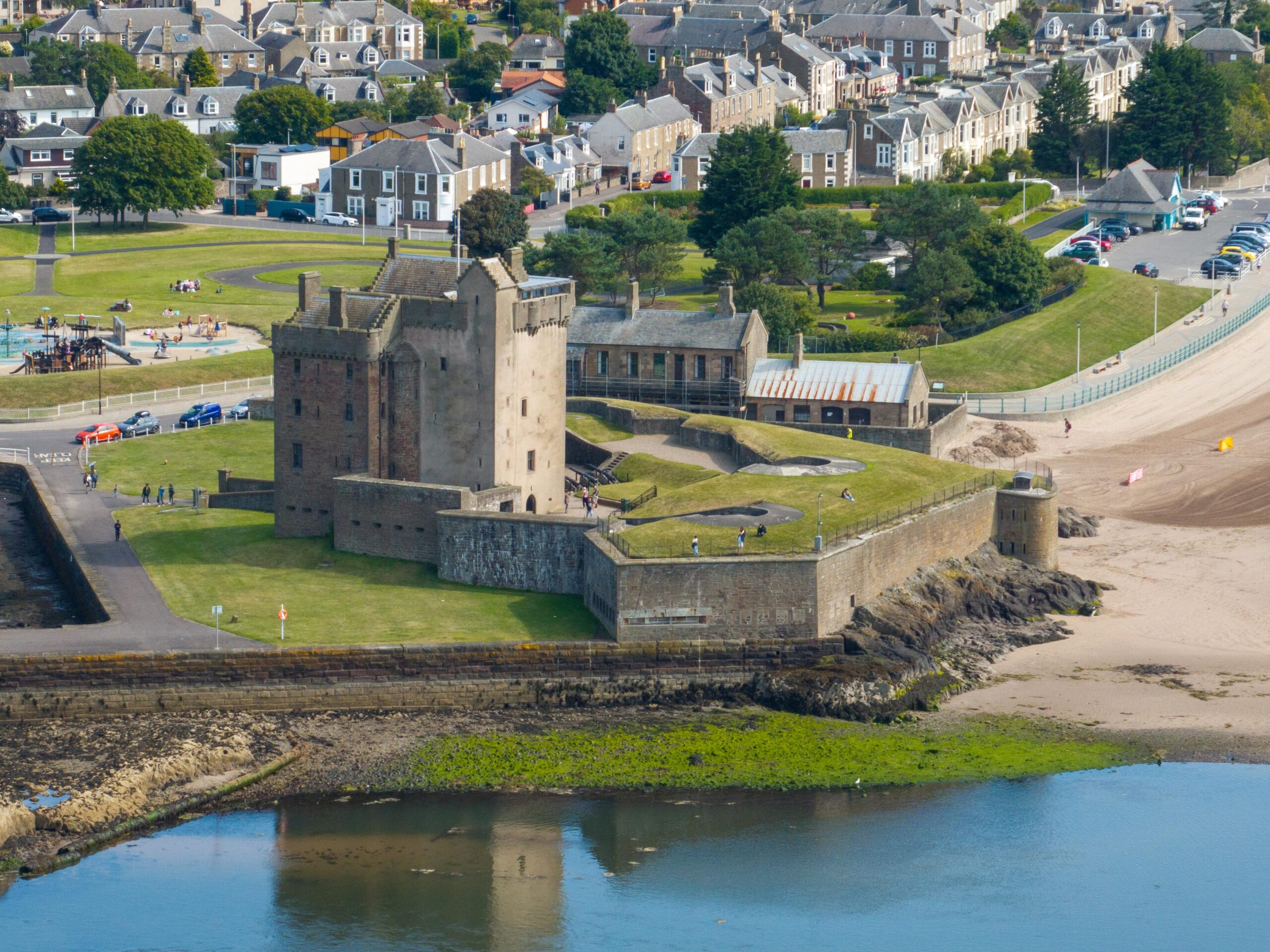 Historic castle on the coast with town visible behind it.