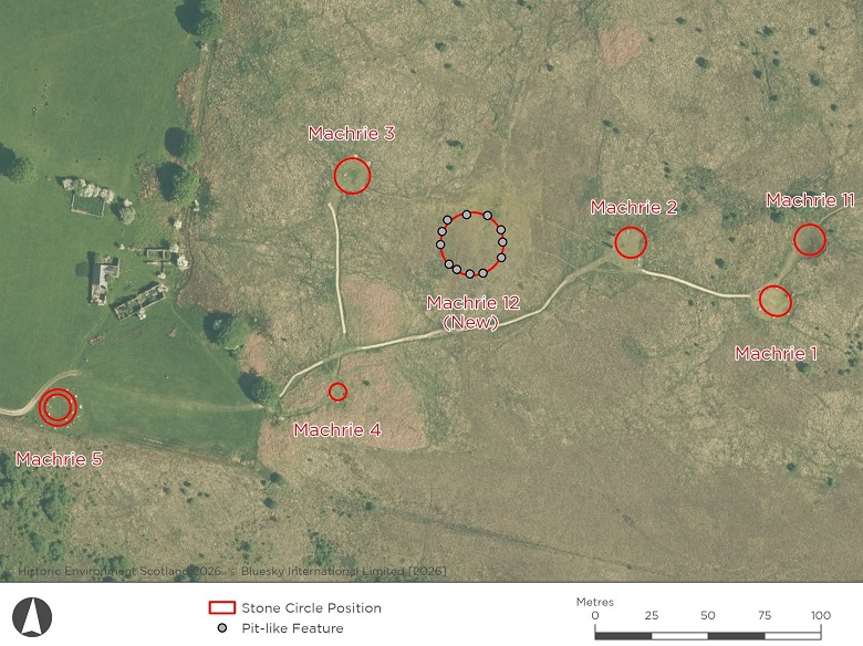 Annotated aerial map of Machrie Moor showing the locations of known stone circles and monuments, including Machrie 1, 2, 3, 4, 5 and 11. A newly identified circle, labelled Machrie 12 (New), is marked near the centre of the image and shown as a ring of pit-like features revealed by geophysical survey. Existing monuments are outlined with red circles.