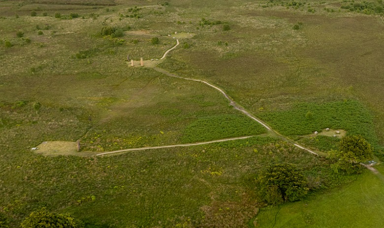 Aerial view of Machrie Moor showing several stone circle and standing stone monuments connected by formal visitor paths. Clearly visible worn "desire lines" cut across the peat between the standing stone monument on the left and the stone circles at the top of the image, where no formal path exists. The informal routes contrast with the established path network and highlight areas of erosion across the moorland landscape.