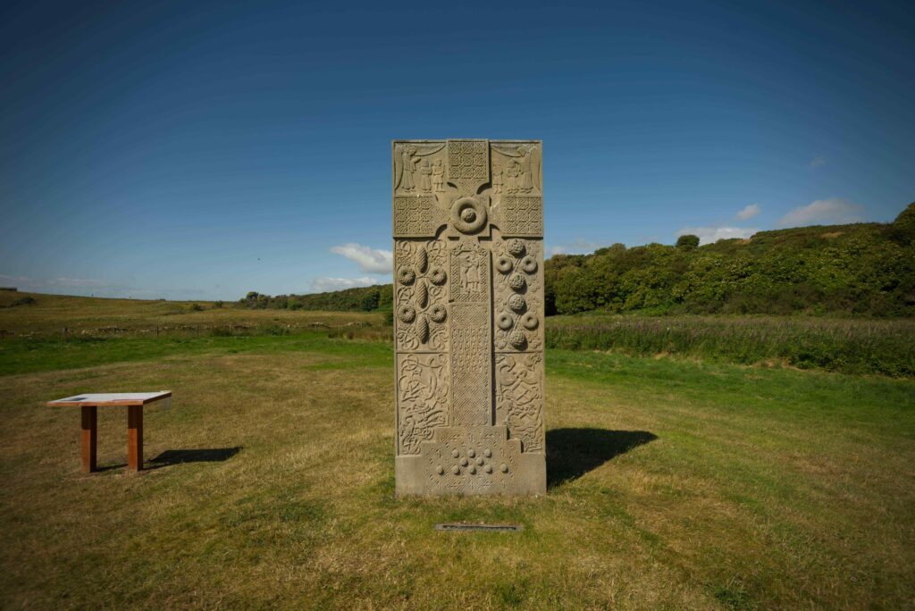 Replica Pictish stone in a field.